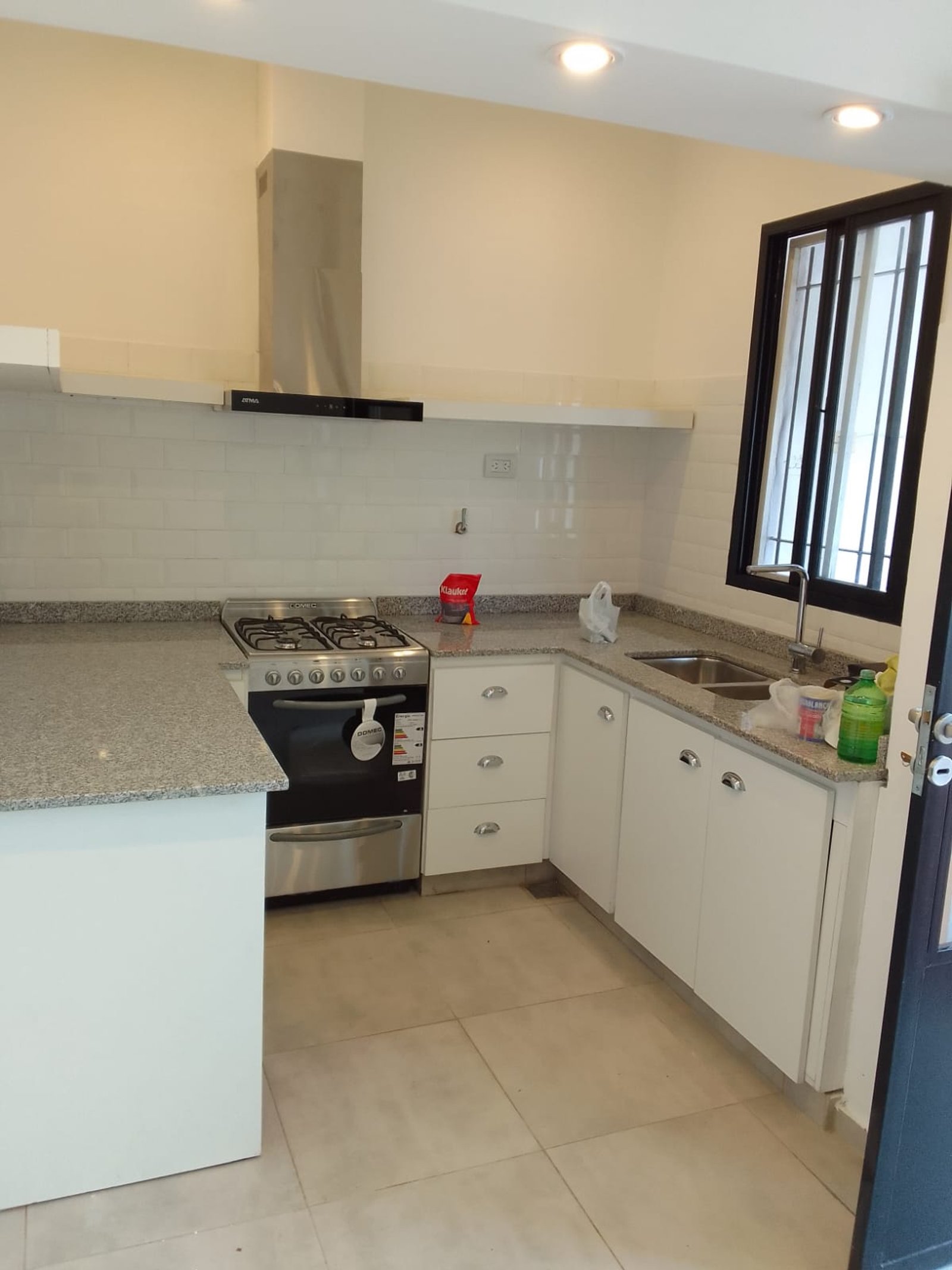 Cocina moderna con muebles blancos y mesada de granito gris — proyecto Casa en Sarandi, por Arquitecto Guido Niccoli, en B1872 Sarandí